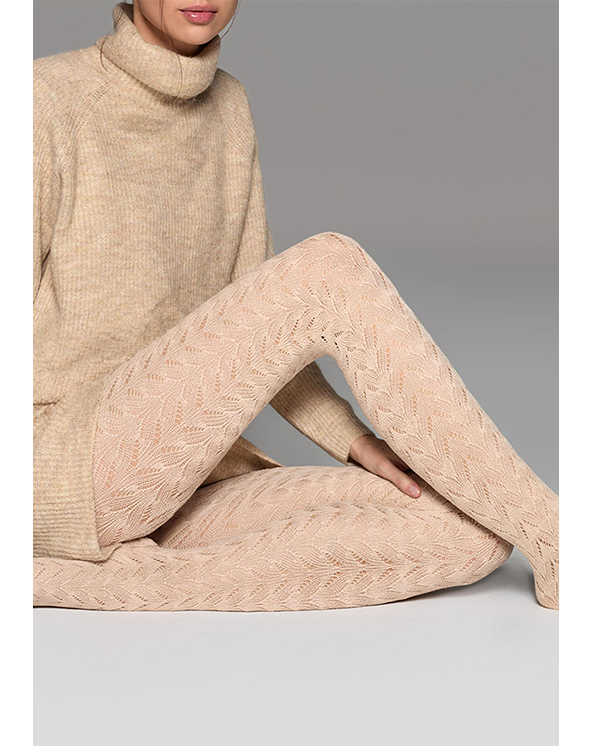 Devojka koja nosi bež rol kragnu i unihop čarape od bambusa na sivoj pozadini.