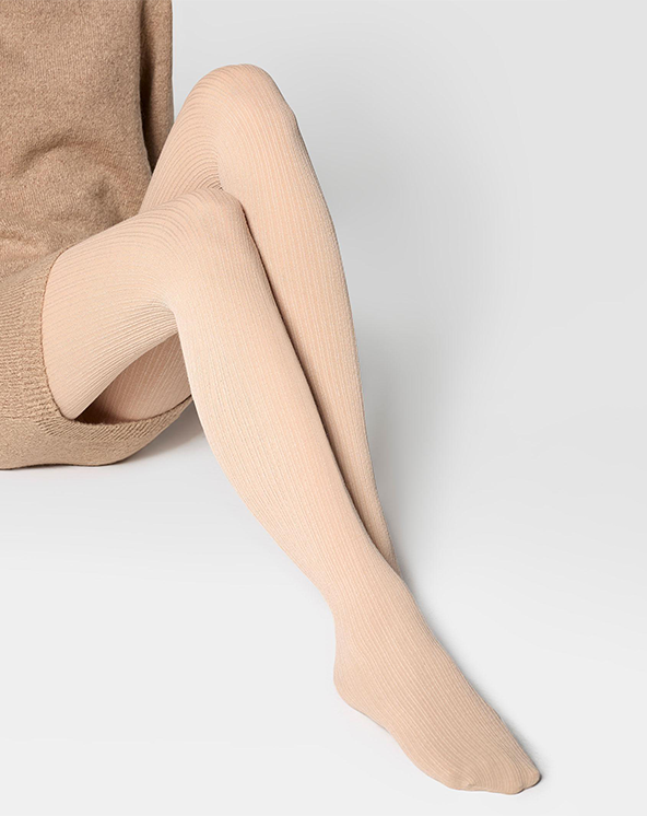 Bež unihop od kašmira koje nosi osoba koja sedi na beloj površini. Slika izbliza.